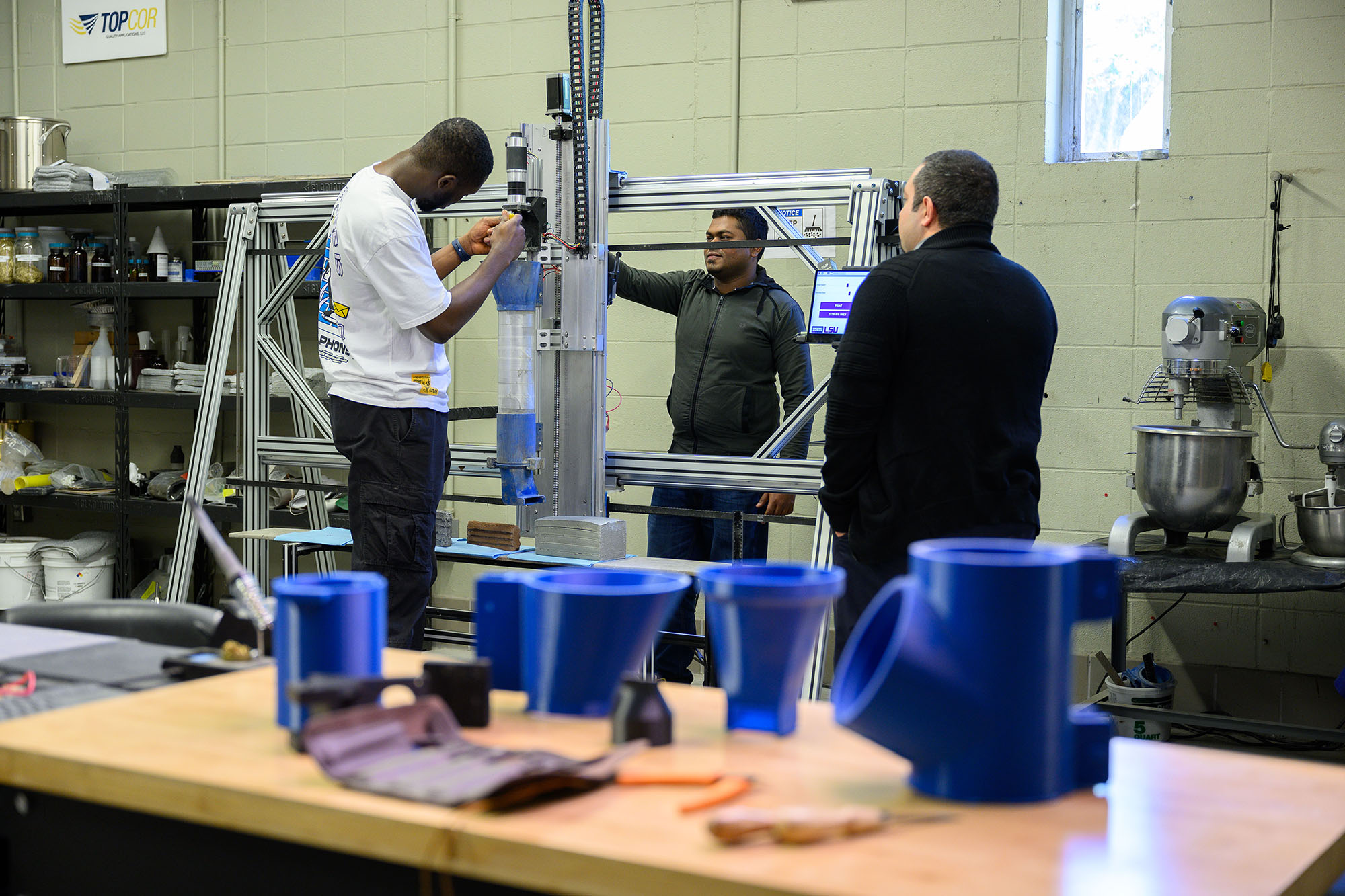 Ali Kazemian in lab watching student work on a machine