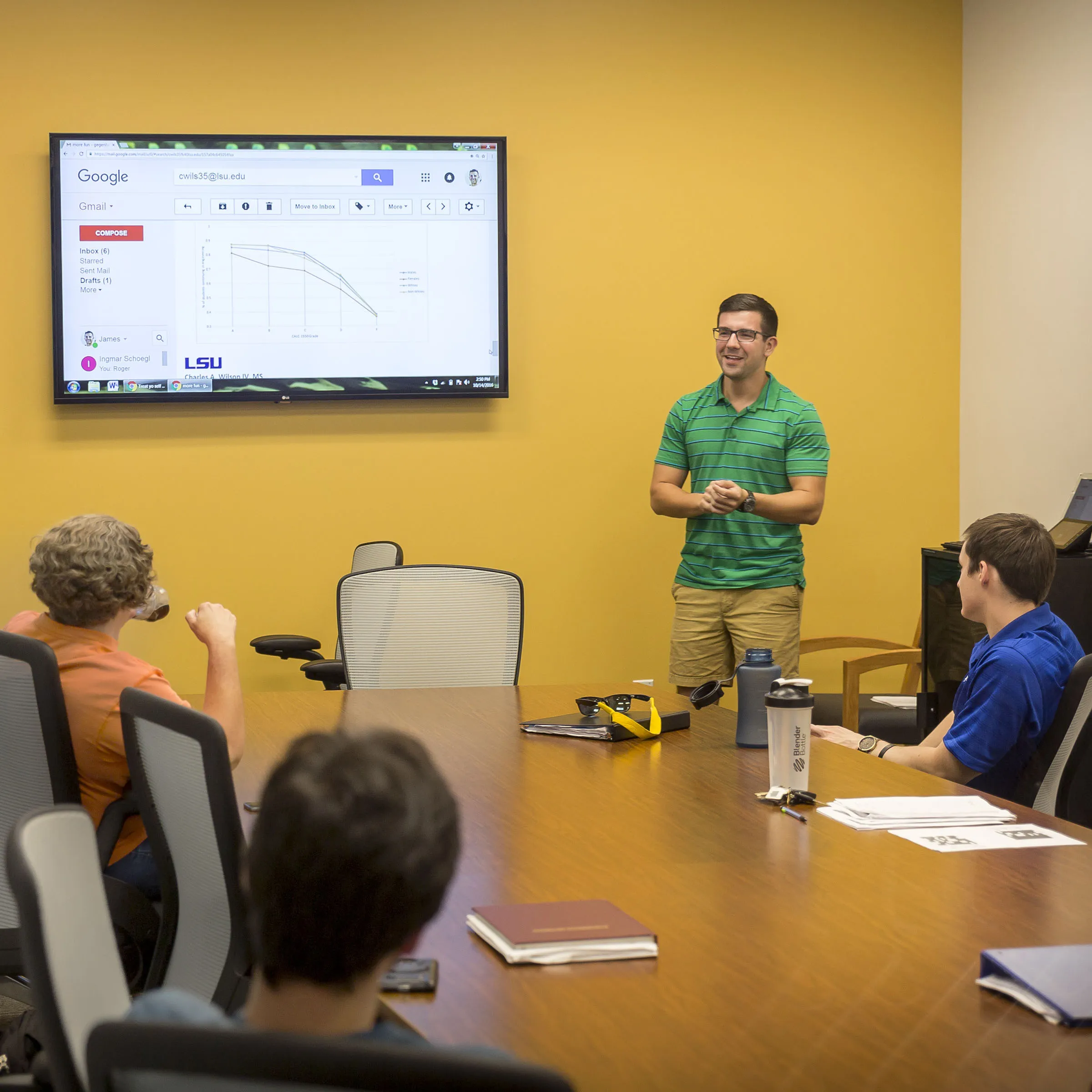 Student presenting in a conference room in front of a screen