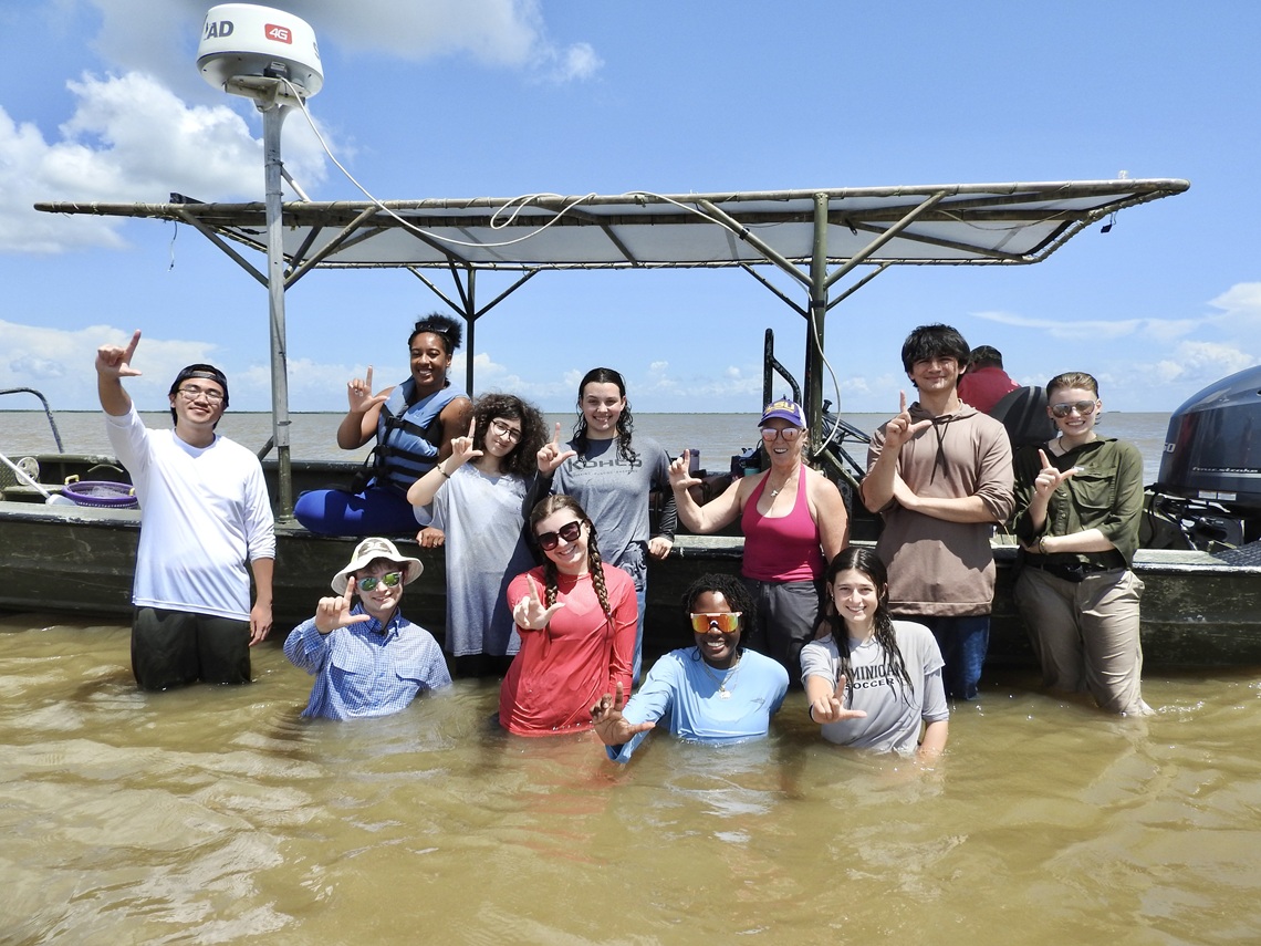 Students posing for a group photo on a boat in the Gulf